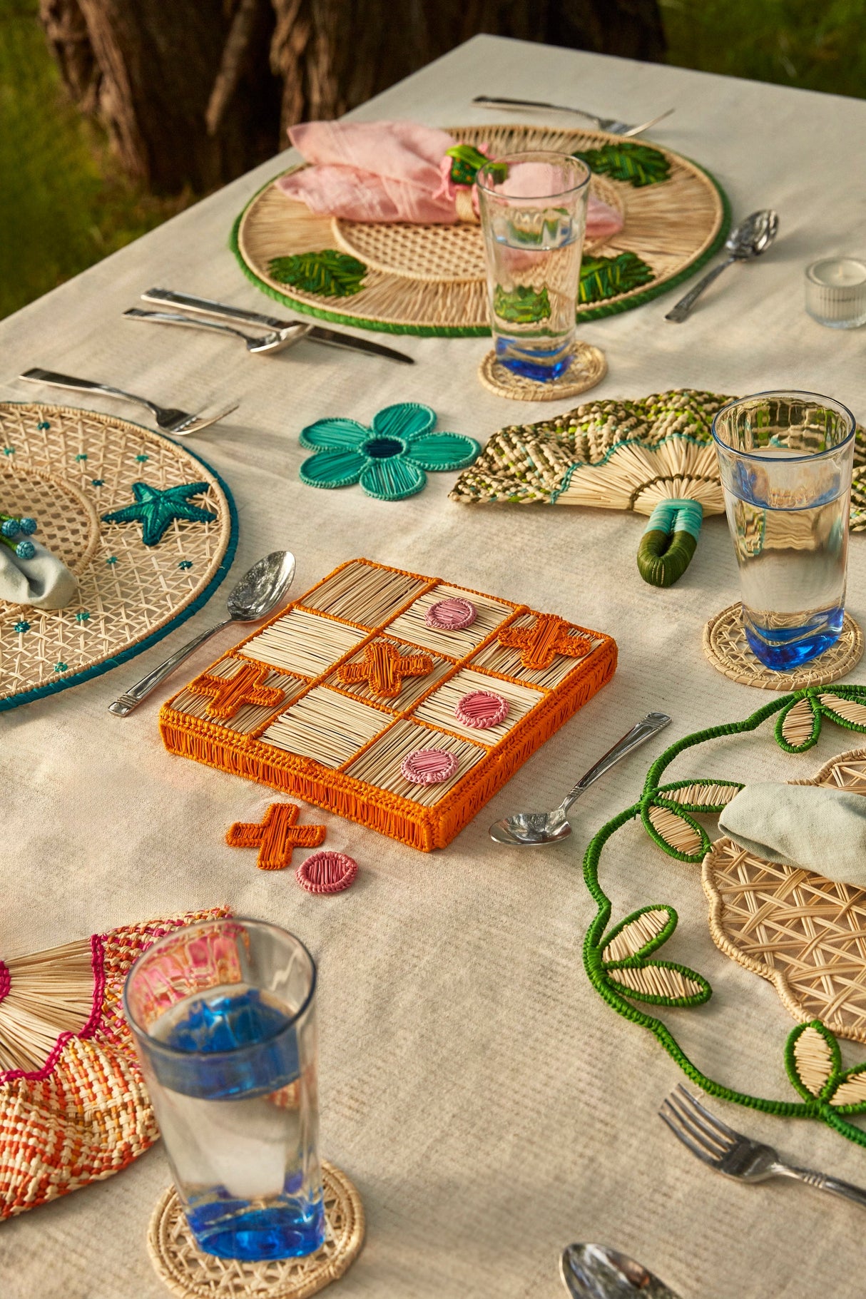 Outdoor table setting with a game board, glasses, and decorative items on a textured surface.