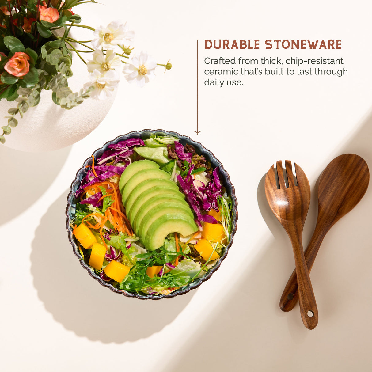 Colorful salad in a durable stoneware bowl with wooden utensils on a light background