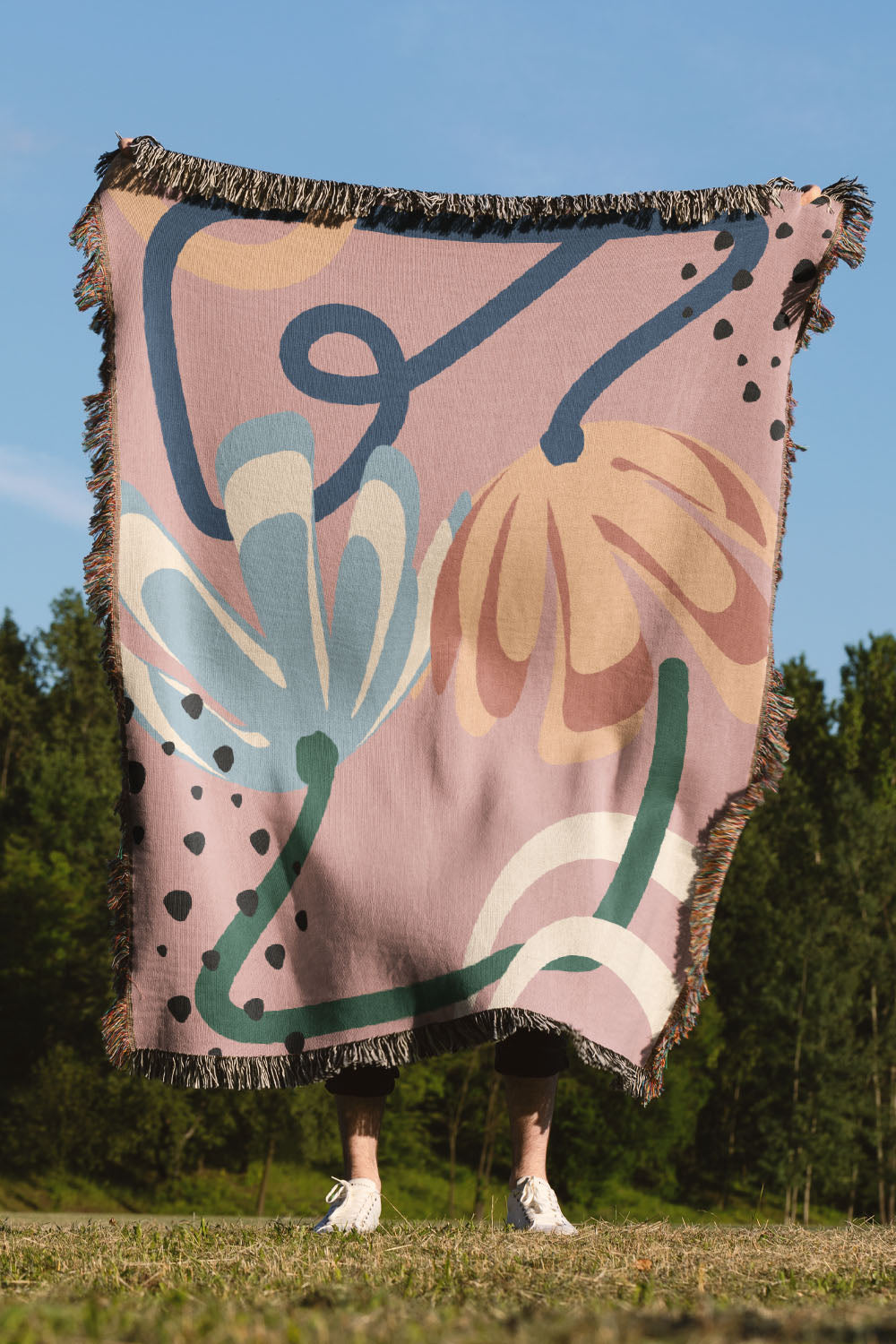Floral-inspired woven cotton throw blanket featuring soft organic shapes and colorful fringe.
