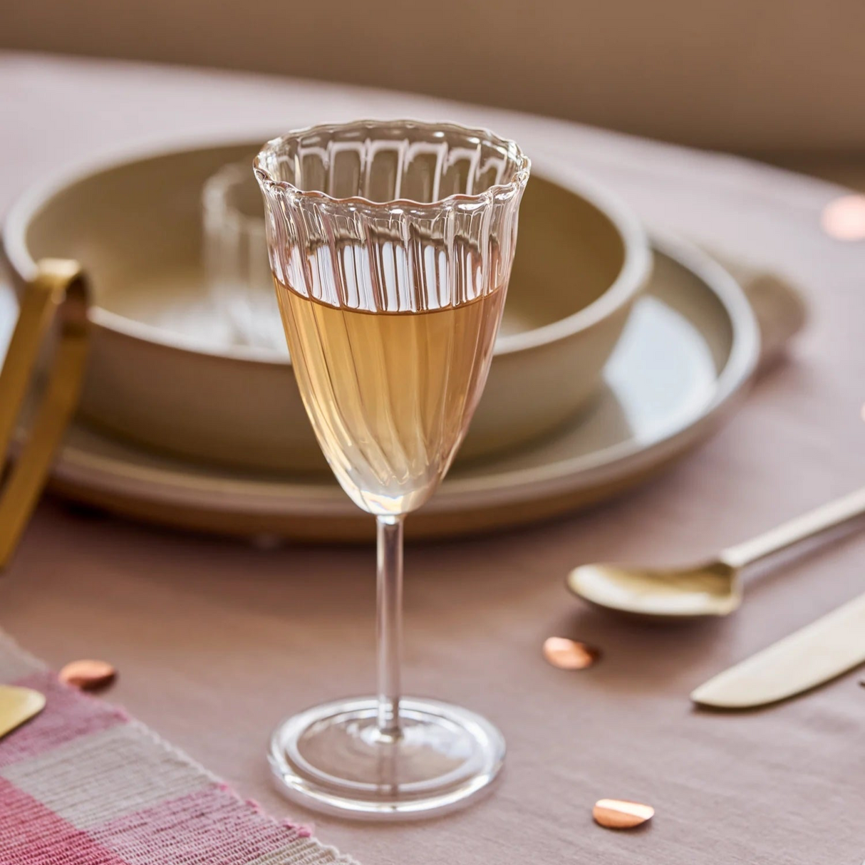 Glass of champagne on a table with plates and cutlery in the background