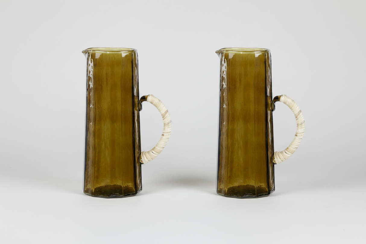 Two glass pitchers with white handles on a light gray background