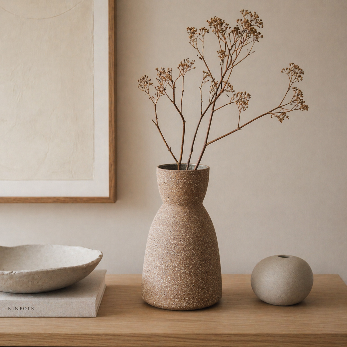 Ceramic vase with dried branches on a wooden surface, with a neutral background