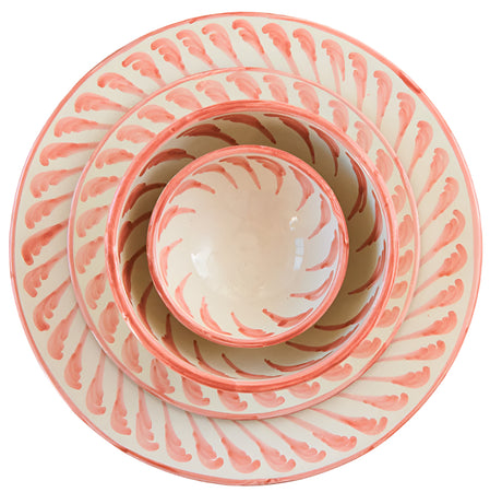 Coral-colored ceramic plates and bowls on a light surface with a spoon and napkin.