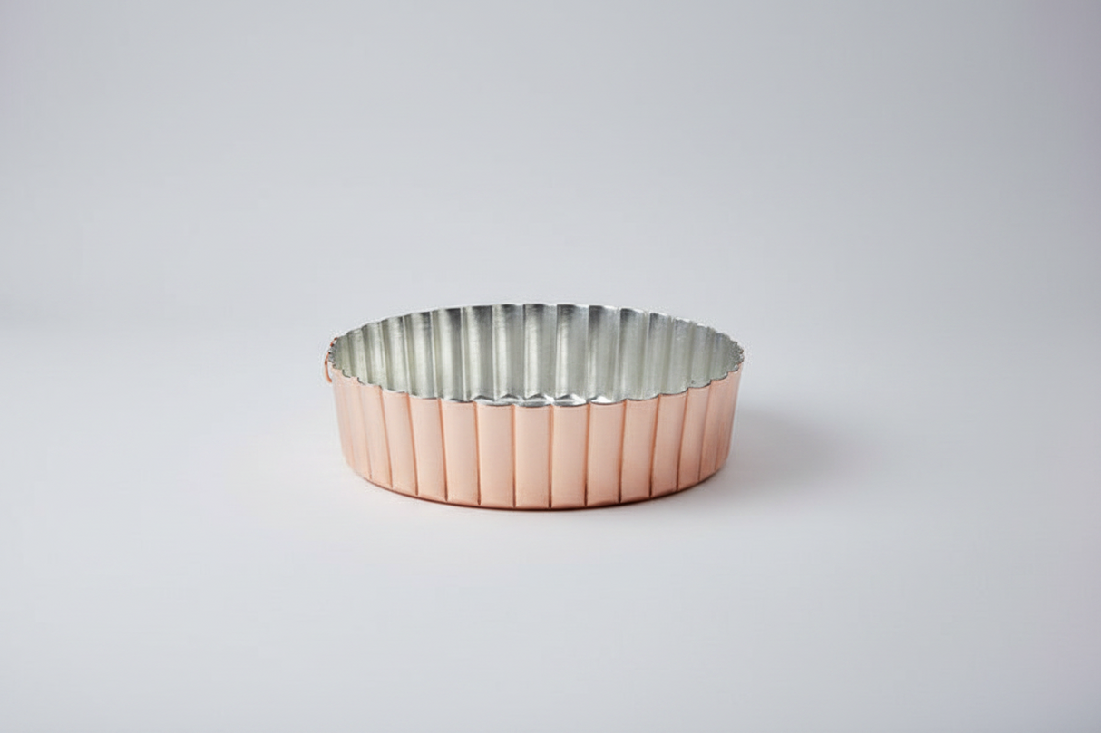 Metallic tart tin with ribbed design on a light gray background