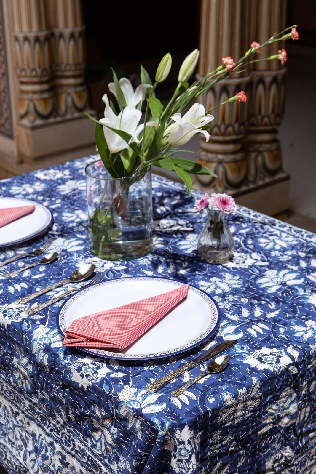 Set table with floral arrangement on a blue patterned tablecloth