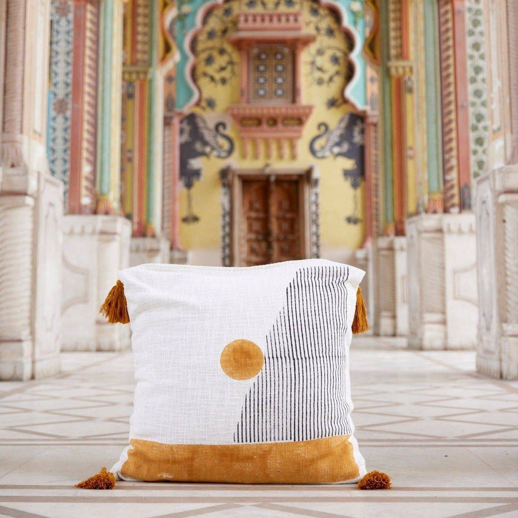 Decorative pillow with tassels on a patterned floor with a colorful architectural background
