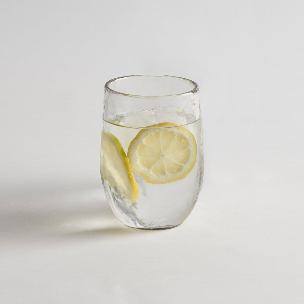 Clear glass with lemon slices on a light gray background