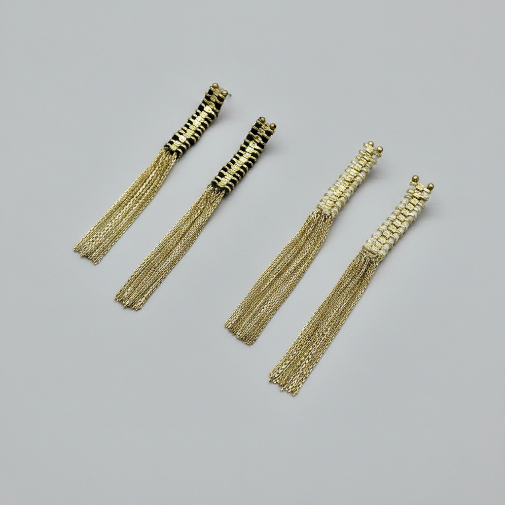 Gold tassel earrings on a gray background
