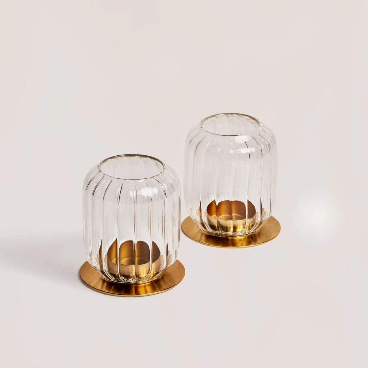 Two glass candle holders with gold bases on a light background