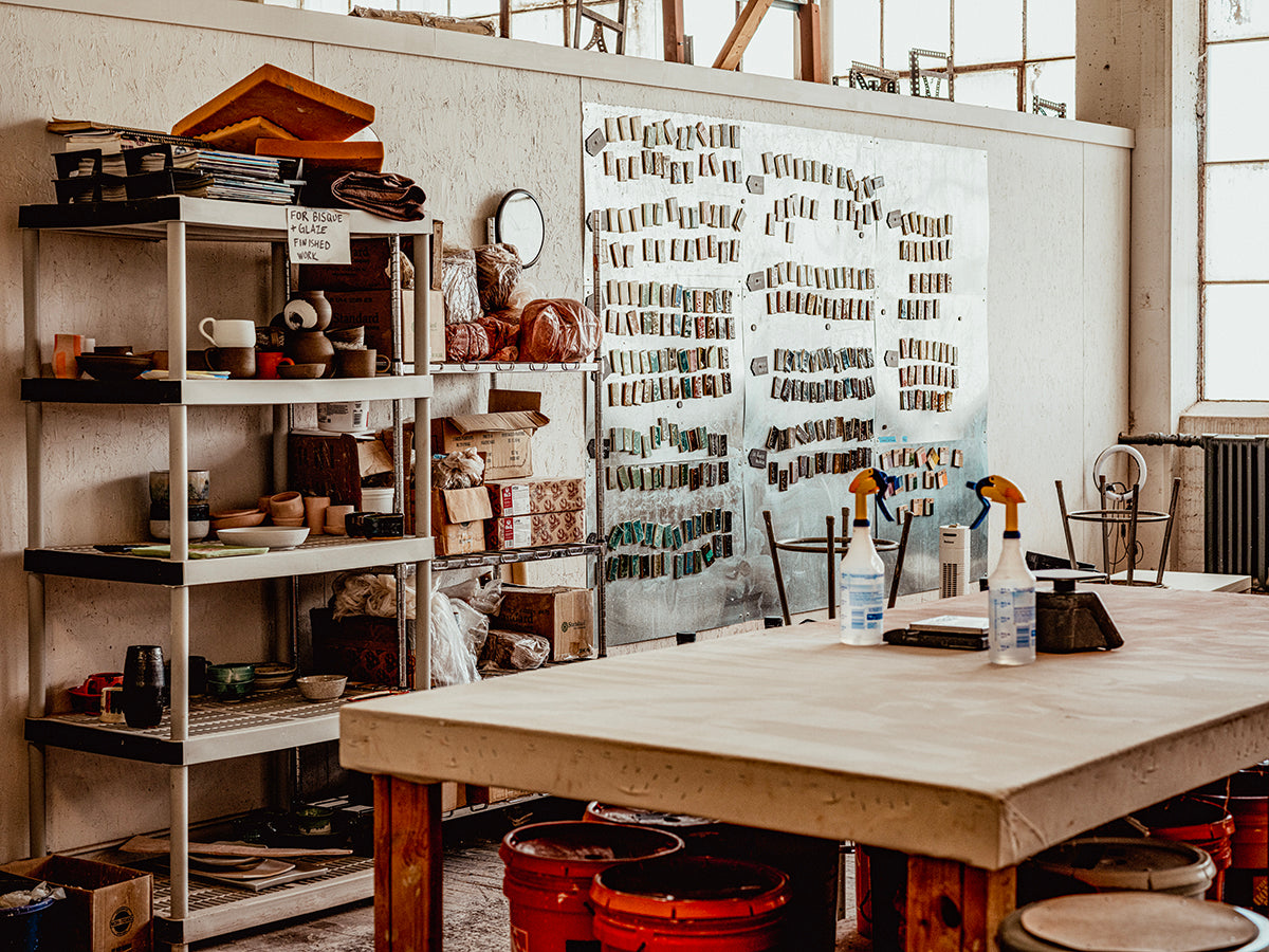 Workshop or studio with shelves, a large table, and various tools and materials.