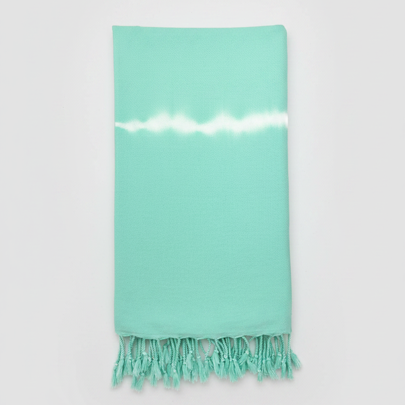Mint green towel with white stripe and fringes on a light gray background