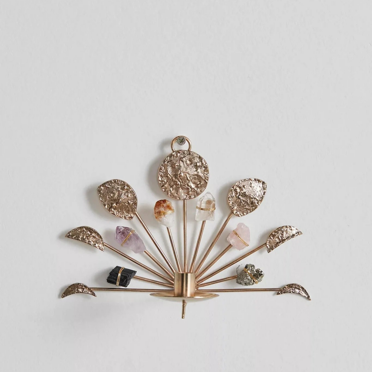 Decorative wall sconce with gold arms and gemstone-like finials on a light gray background