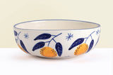 Ceramic bowl with blue leaf and orange design on a white background