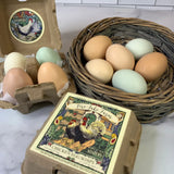 Eggs in a carton and basket with a box of  chicken egg soaps on a marble surface.