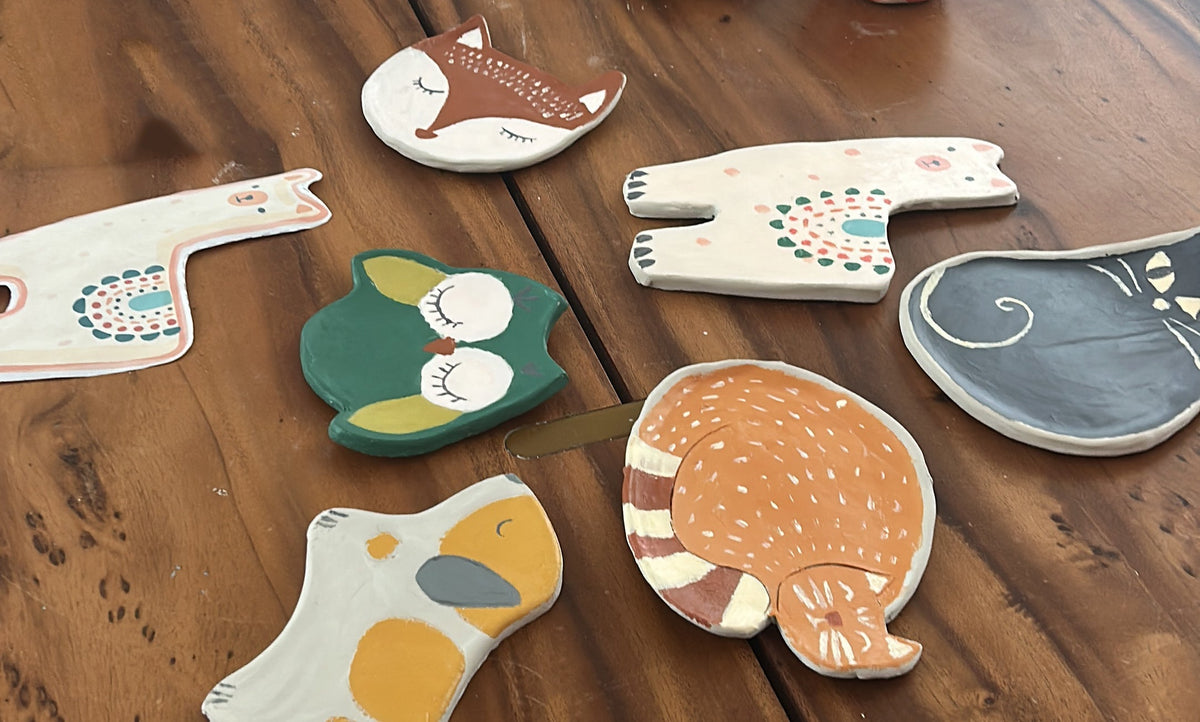 Set of colorful animal-shaped ceramic plates on a wooden surface