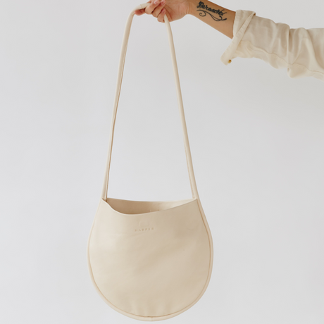 Beige handbag held by a person against a white background