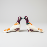 Two ceramic birds with floral designs on a white background