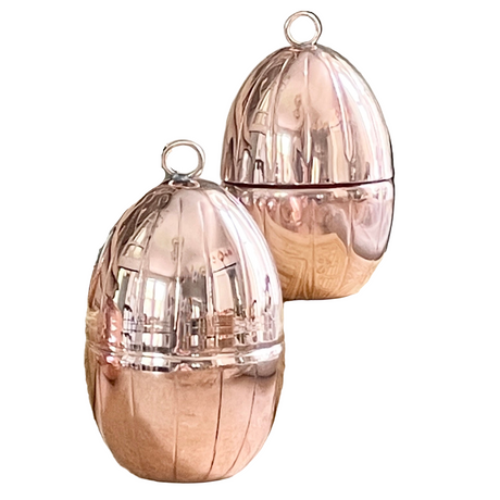 Two copper egg ornaments on a white background