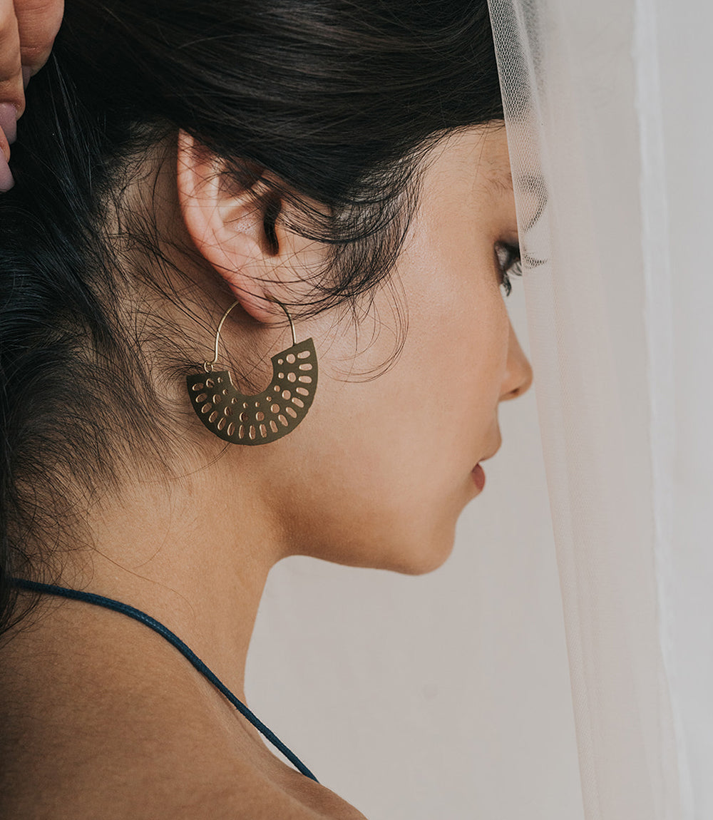 Close-up of a woman wearing a gold hoop earring with a neutral background