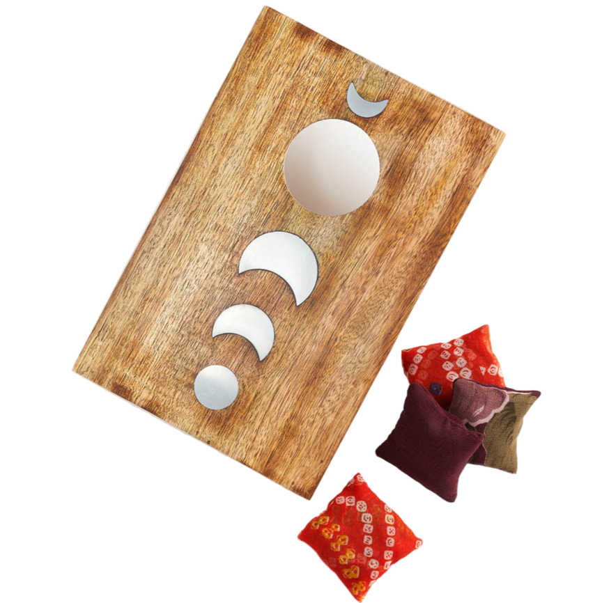 Wooden board with moon phase cutouts and decorative pillows on a white background