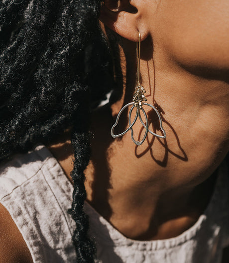 Close-up of a person wearing a delicate silver earring with a textured background