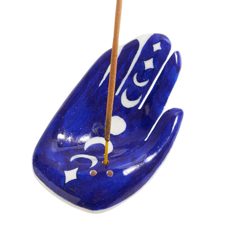 Blue hand-shaped incense holder with a single incense stick on a white background