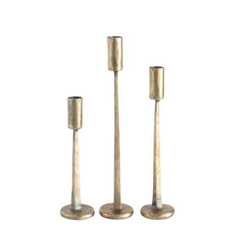 Set of three brass candle holders on a white background