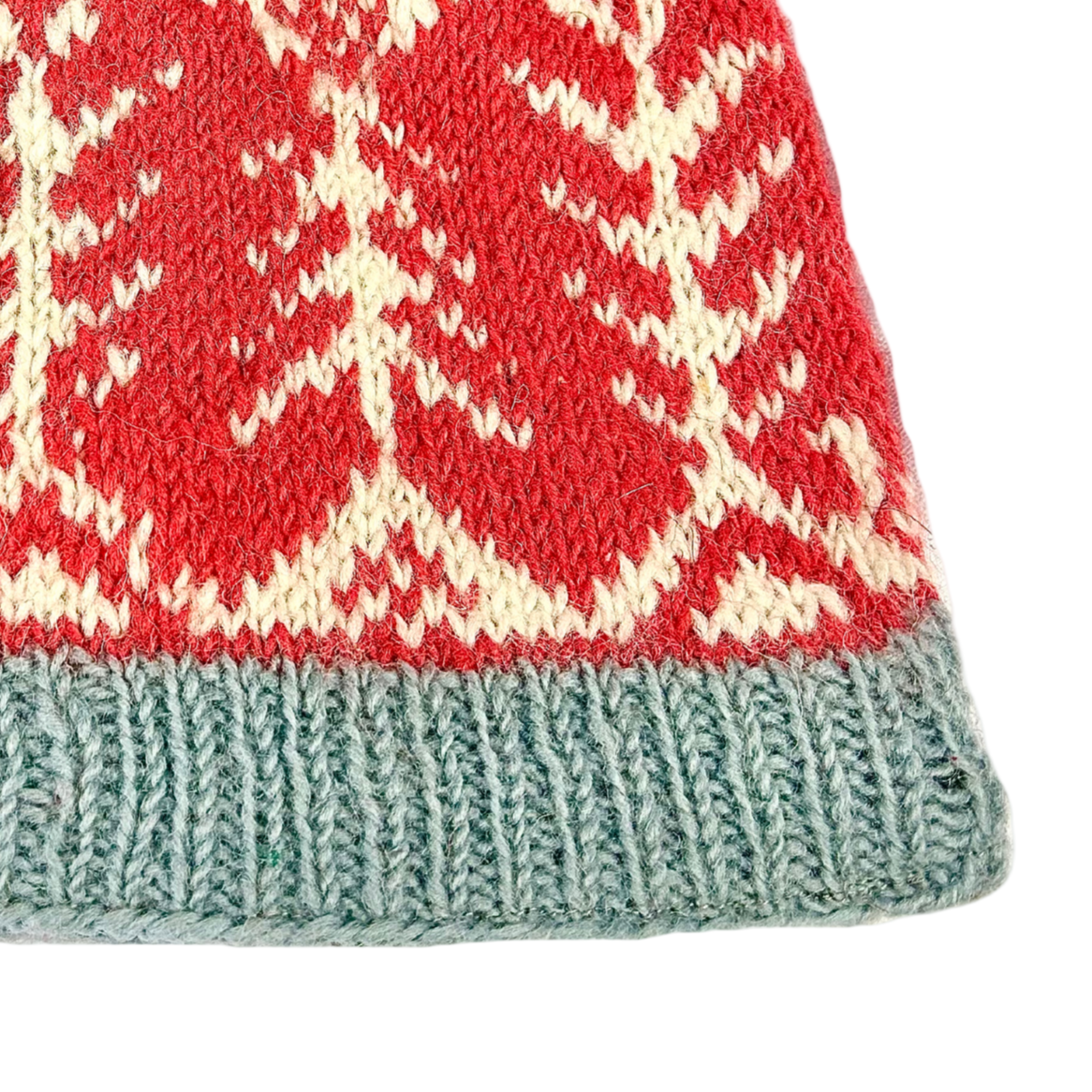 Close-up of a knitted fabric with red, white, and green pattern on a white background