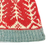 Close-up of a knitted fabric with red, white, and green pattern on a white background