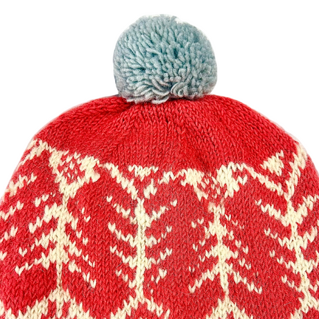 Red knit beanie with white pattern and gray pom-pom on a white background