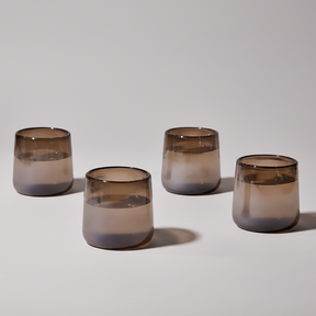Four smoked glass tumblers on a light gray background