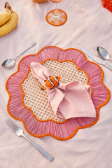 Decorative pink and orange placemat with a folded pink napkin and butterfly decoration on a light background.