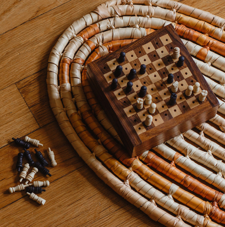 Wooden chess set with pieces on a woven mat on a wooden floor