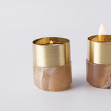 Two brass candle holders with marble bases on a light gray background