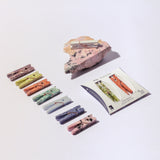 Set of colorful stone clothespins on a white background with a rock and card.