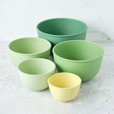 Set of five green bowls on a light gray surface