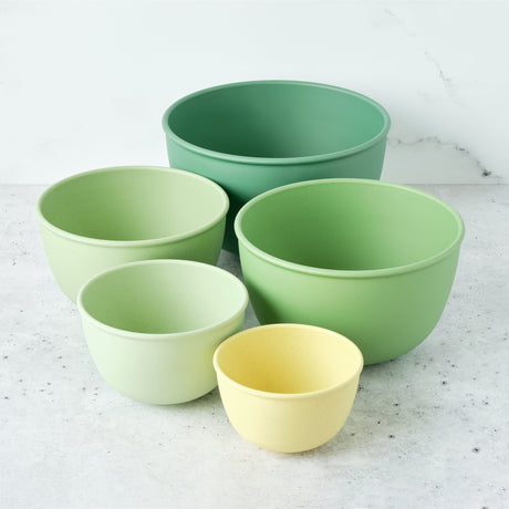 Set of five green bowls on a light gray surface