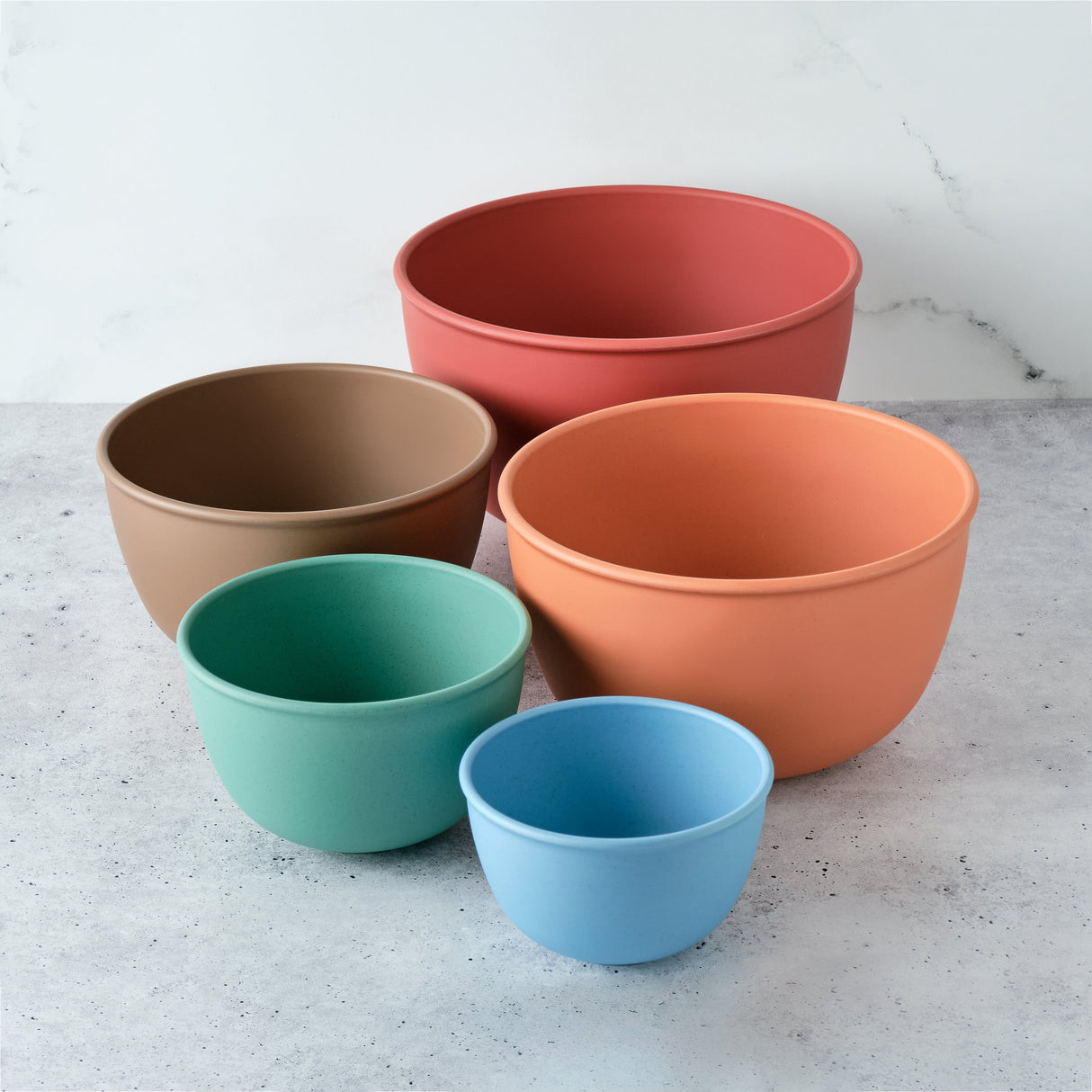 Set of five colorful bowls on a light gray surface with a white background