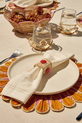 Decorative table setting with a plate, napkin, and colorful placemat on a beige surface.