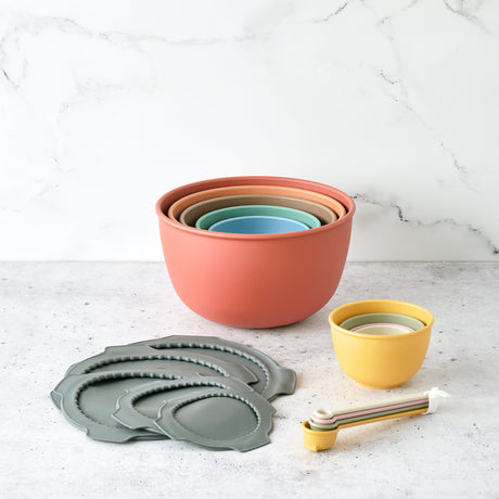 Set of colorful nesting bowls and measuring cups on a light surface with a white background