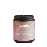 Kandu candle with a visible flame on a white background