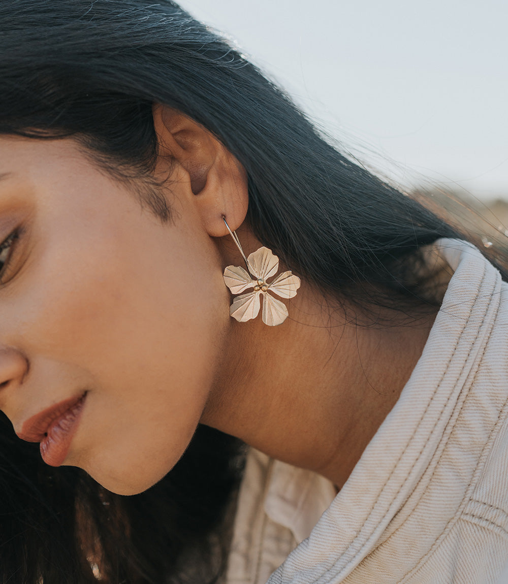 Close-up of a person wearing a floral earring outdoors