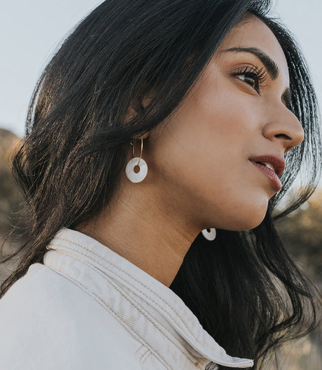 Woman wearing gold hoop earrings with a blurred natural background