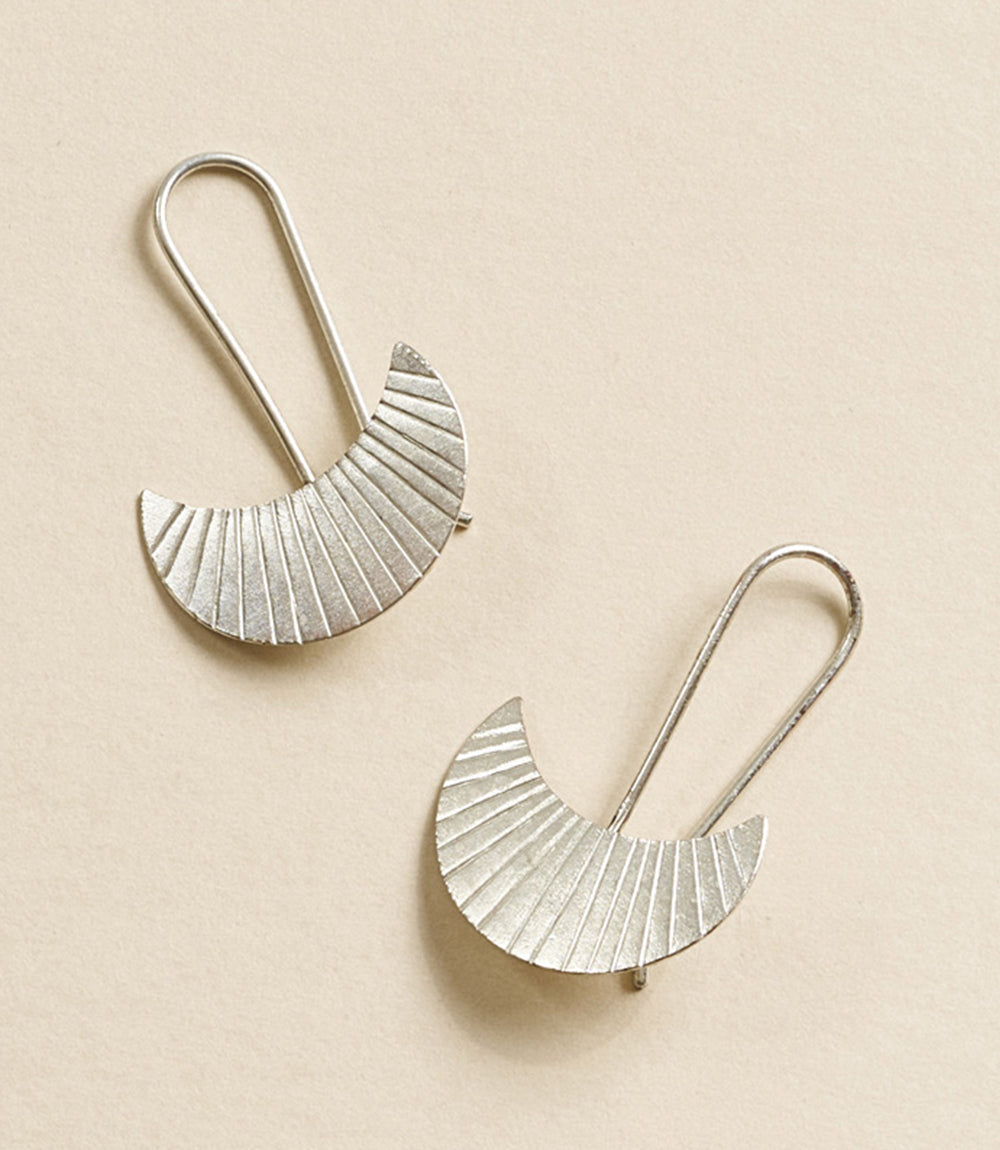 Pair of silver earrings on a beige background