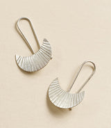 Pair of silver earrings on a beige background