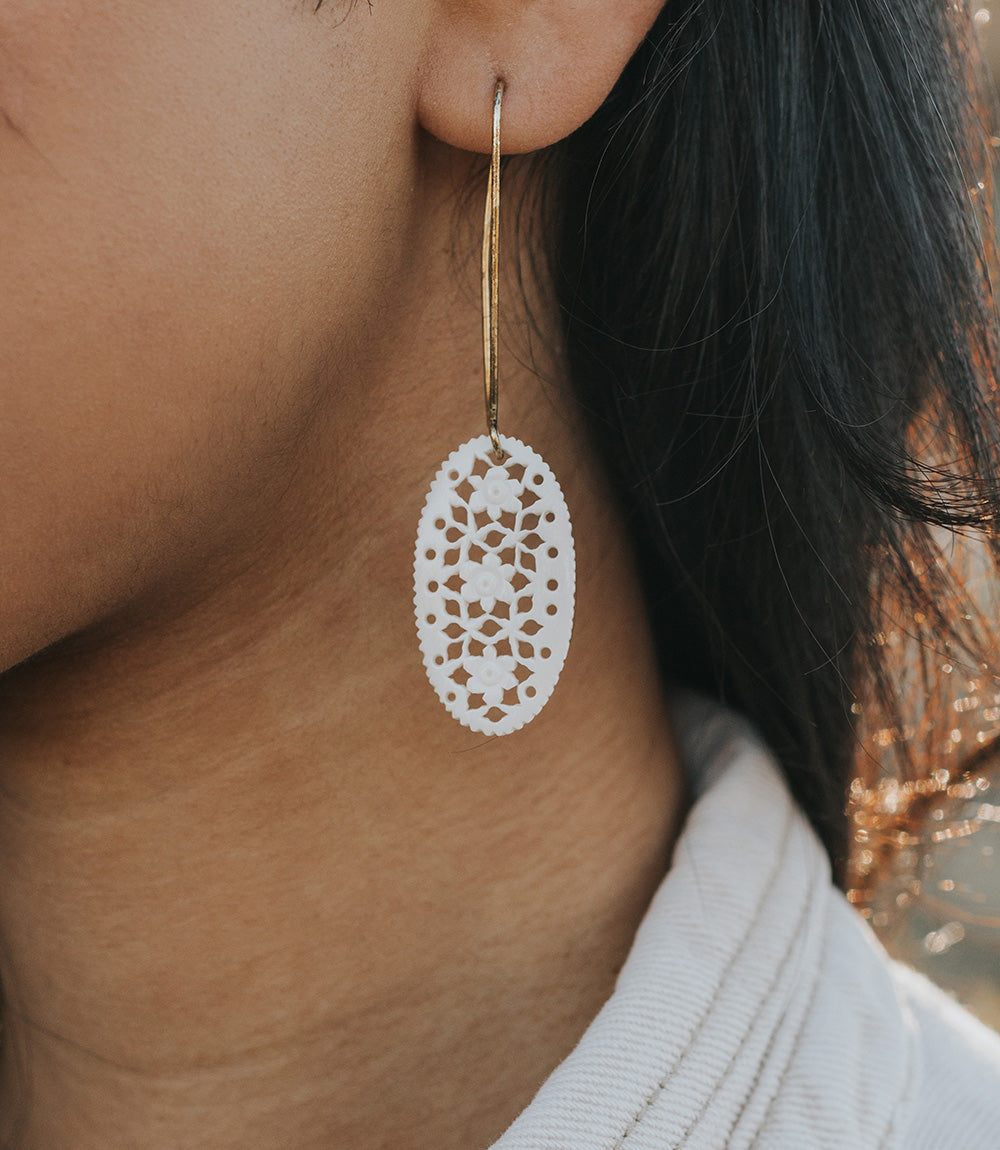 Close-up of a person wearing a white lace earring with a blurred background