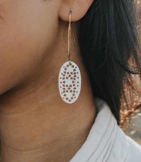 Close-up of a person wearing a white lace earring with a blurred background