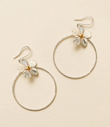 Gold hoop earrings with floral designs on a beige background