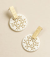 Pair of earrings with gold and white lace-like designs on a beige background