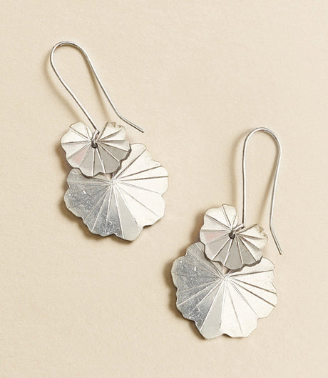 Silver leaf-shaped earrings on a beige background